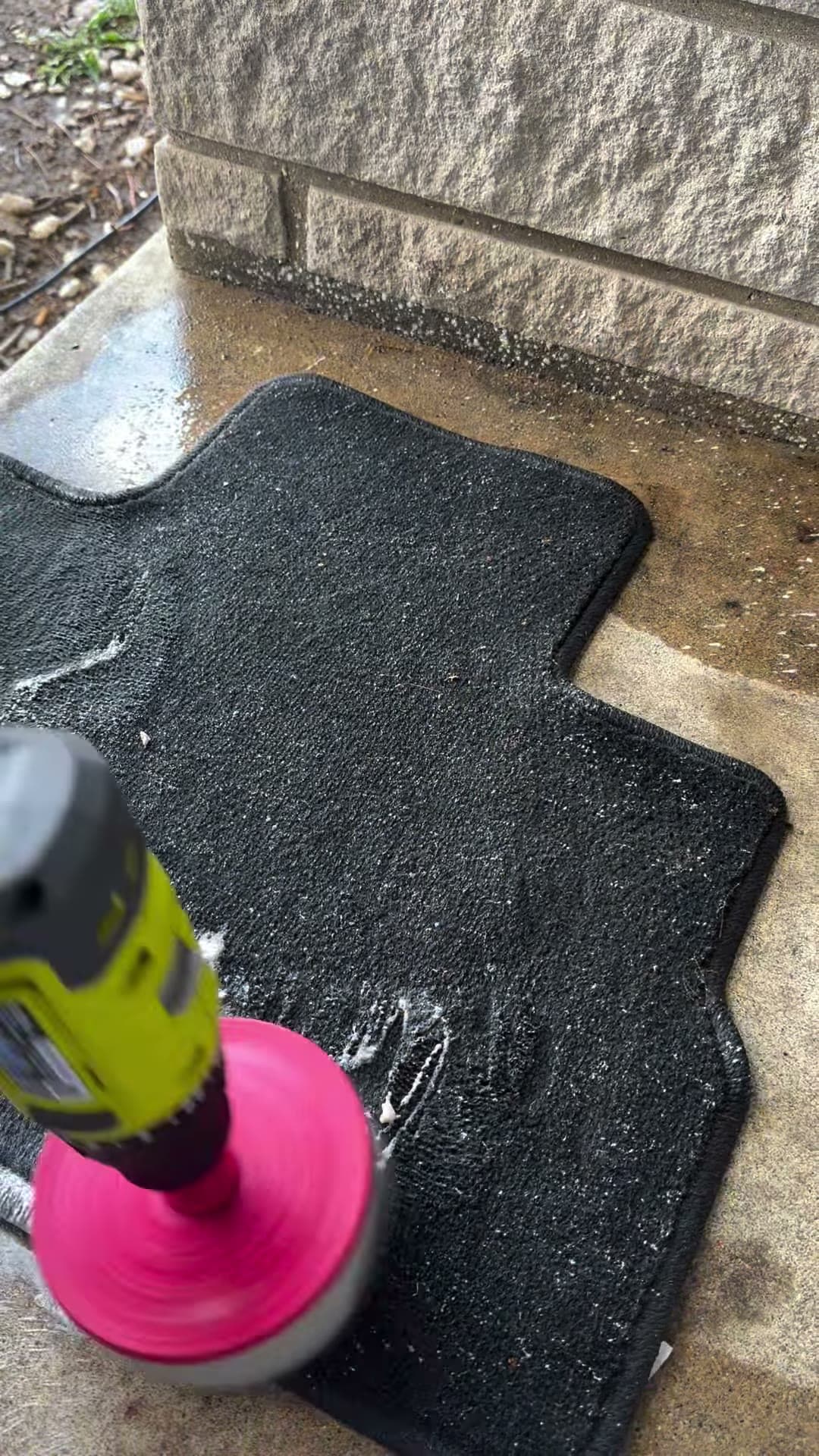 Powered brush agitating a vehicle floor mat
